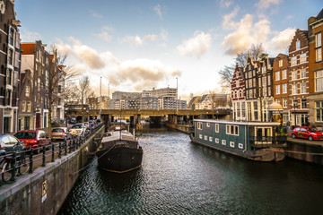 Fototapeta premium AMSTERDAM, NETHERLANDS - JANUARY 10, 2017: Famous vintage buildings & chanels of Amsterdam city at sun set. General landscape view. January 10, 2017 - Amsterdam - Netherlands..