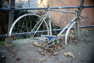 Verwahrlostes Fahrrad / Ein alter Fahrradrahmen hängt angekettet und vergessen an einem Zaun.