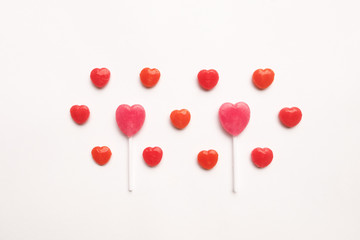 Pink Valentine's day heart shape lollipop with small red candy in cute pattern on empty white paper background. Love Concept. colorful hipster style. Knolling top view.