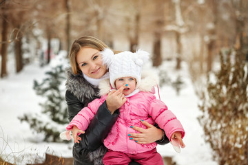 Fototapeta premium Mother and daughter outdoors frost. Mother touching her daughter's nose. Family walk in a winter park. Family happiness.