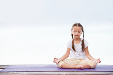 Fototapeta na wymiar Child doing exercise on platform outdoors. Healthy lifestyle. Yoga girl
