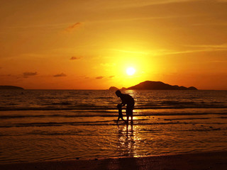 father and son on the beach in vacation in sunset
