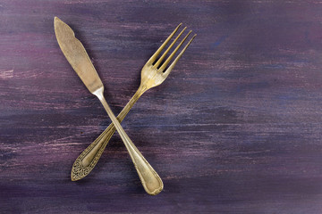 Vintage fork and knife on purple with copyspace
