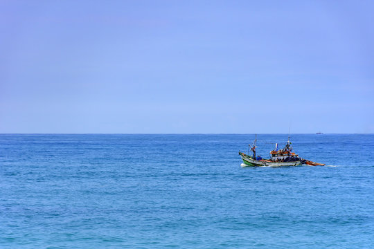 Fishing boat on the horizon sailing over the sea in Rio de Janeiro.