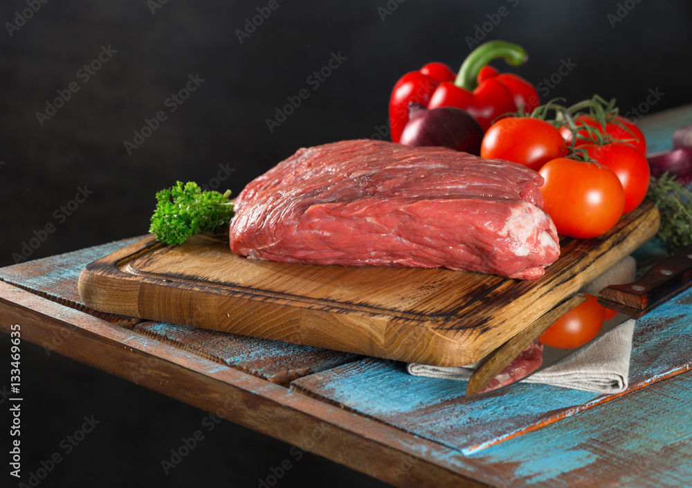 Wall mural raw beef fillet with vegetables on wooden table