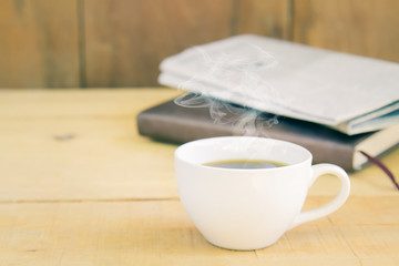 Hot coffee have smoke and book, newspaper morning relax time on wood table with copy space. Vintage retro style.