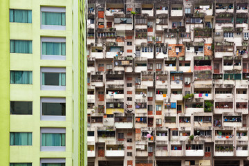 Fototapeta na wymiar Geometrical pattern of multistory apartment house with group of windows and tenant lumber on balconies. Asian cities street background. Cheap accommodation, social problems in overcrowded countries.