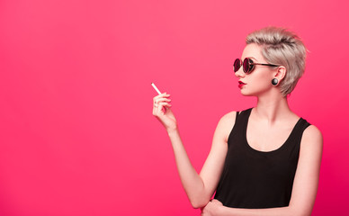 young woman with short blond hairstyle smoking a cigarette.