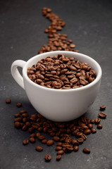 Natural organic roasted coffee beans in white cup on black background, selective focus