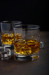 Glass of whiskey with ice on the old rusty background