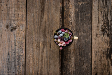 frozen berries, black currant, red currant, raspberry in enamel mug decorated by currant leaf on wooden table in rustic style,  top view.