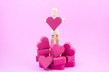 Wooden dummy holding paper box red heart shape on pink backgroun