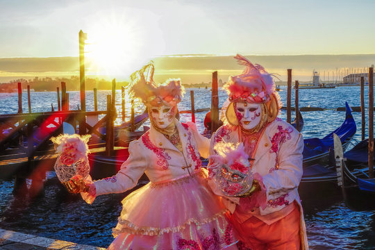 Famous carnival masks against gondolas in Venice, Italy