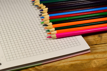 Obraz premium Notebook with colour pencils on the wooden table