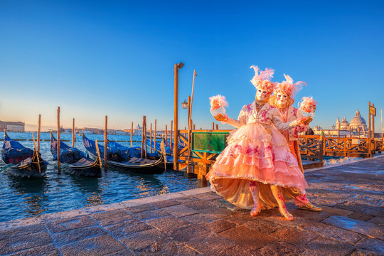 Fototapeta Famous carnival masks against gondolas in Venice, Italy