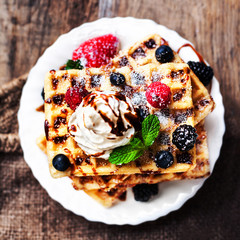 Belgian waffles with ice cream, fruits, syrup and icing. Homemad