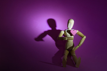 Wooden dummy and a paper box red heart shape on pink background