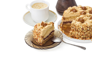 Partly sliced layered sponge cake on background of coffee