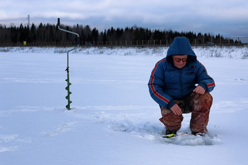 Fototapeta na wymiar Winter season old man fishing on lake
