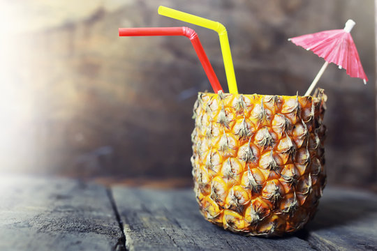 pineapple with straw and cocktail umbrella Photos | Adobe Stock