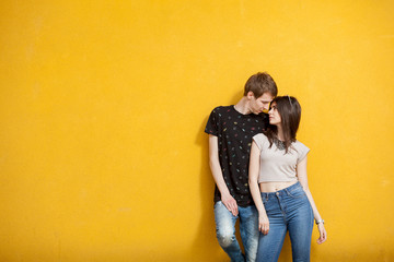 Fototapeta na wymiar Inlove couple posing in fashion style on yellow wall