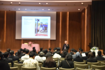 Blurred image of education people and business people sitting in conference room for profession seminar and the speaker is presenting new technology and idea sharing with the content activity.