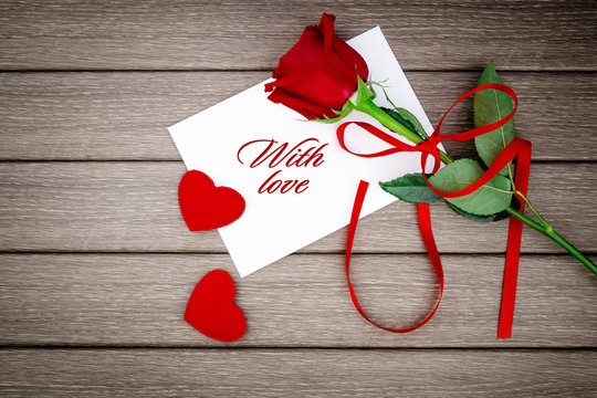 Romantic love letter with red rose on wooden