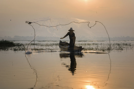 fisherman acting in throwing a net catching fish in lake morning scenery view
