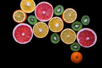 Slices of grapefruit, kiwi and orange arranged in the form of US map. Fruits on a black background closeup