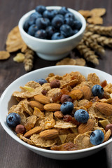 cereal flakes with blueberries and nuts on a dark  table
