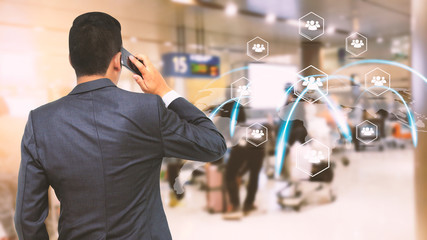 Businessman with smartphone talking at airport terminal.