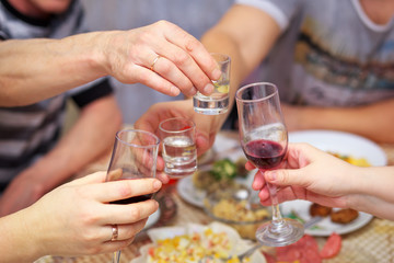 People drink at the table, clink glasses. Cheers
