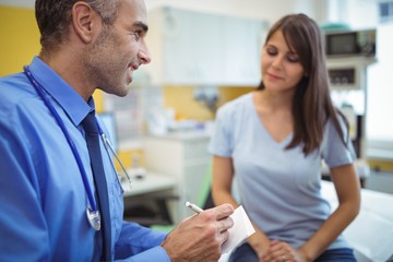 Obraz premium Doctor interacting writing on paper while consulting patient