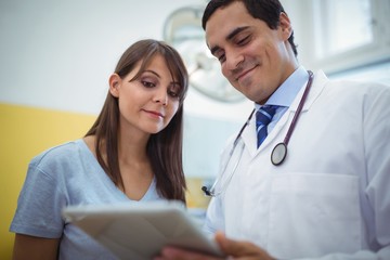 Doctor assisting female patient on digital tablet