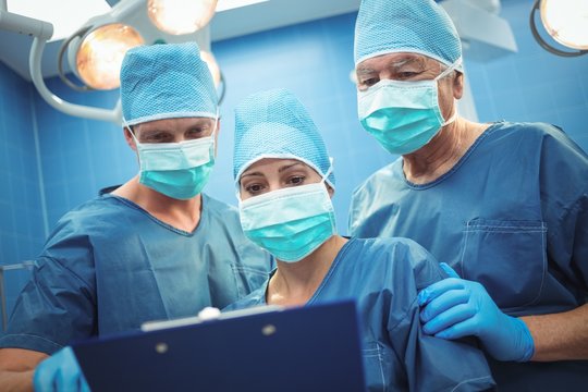 Team of surgeons discussing over clipboard in operation theater