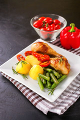 the baked chicken legs with vegetables in a plate on a table, selective focus, copy space
