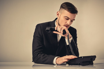 young man dials the phone number while sitting in the office