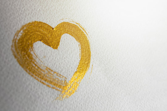 Gold heart brush stroke on white drawing paper, selective focus and depth of field