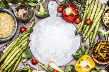 Various healthy vegetarian ingredients with Pearl barley around round cutting board, top view frame. Clean eating or diet food concept