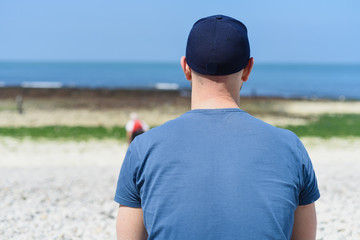 Man on the beach looking at the endless sea distance