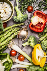 Various colorful vegetables ingredients with cooking spoon and feta cheese for tasty cooking, top view. Healthy vegetarian food or diet nutrition concept