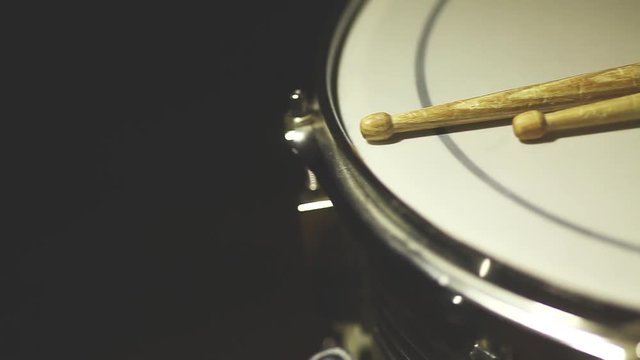 Dolly shot of a snare drum and a pair of drumsticks.