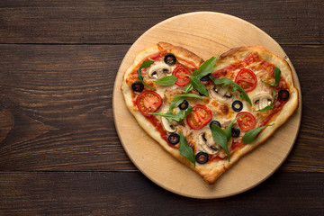 Heart shaped pizza on cutting board on wooden table. - 133489299