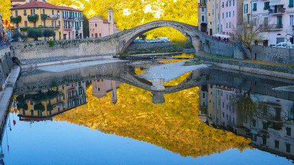 Reflections on the water of the roman bridge in the village of Dolceacqua, Imperia, Italy