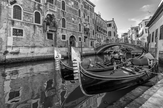 Fototapeta Black and white view of typical traditional gondolas parked in a Venetian canal, Fondamenta dei Preti, Venice, Italy