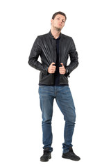 Fototapeta premium Young casual man posing and pulling leather jacket collar. Full body length portrait isolated over white background.