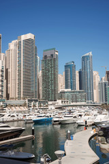 Dubai harbor with boats and yachts on a mooring, on skyscrapers background, vertical