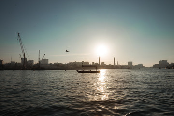 silhouette of a boat floats on the sea channel of Dubai on the background of the setting sun, the long-range plan, Dubai