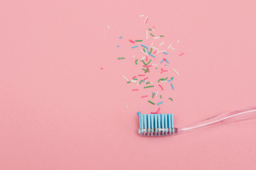 blue toothbrush on pink background with sprinkles. minimal pastel flat lay fashion style.