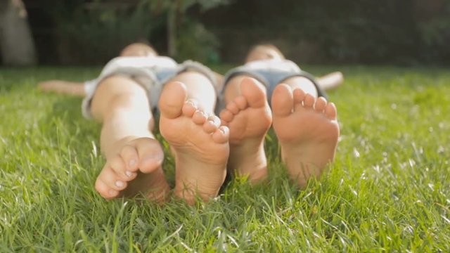 Dolly shot of two girls feet lying on grass at park